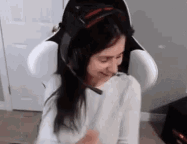 a woman is sitting in a chair wearing headphones and smiling .