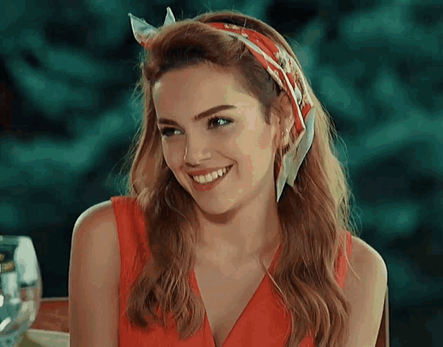 a woman wearing a red dress and a headband smiles