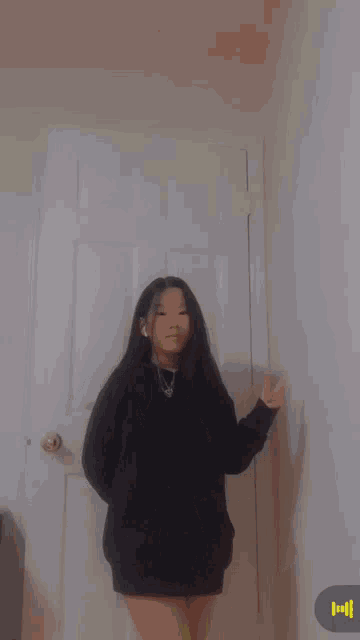 a girl is standing in front of a door and giving a peace sign