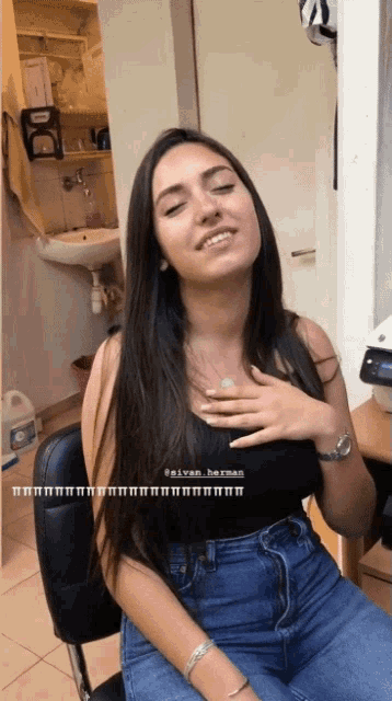 a woman is sitting in a chair with her hands on her chest and the name @silvan_berman is on the bottom right