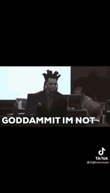 a man is sitting in front of a microphone in a courtroom and saying `` goddammit im not '' .
