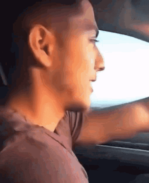 a man is driving a car with his eyes closed and his mouth open .