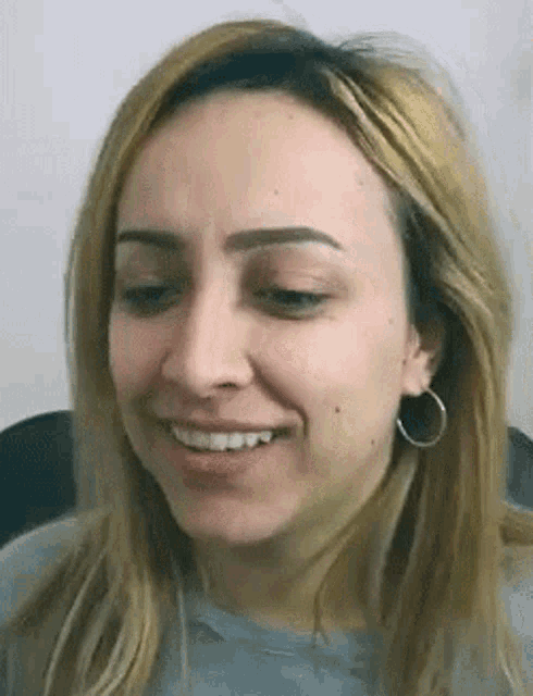 a close up of a woman 's face with blonde hair and hoop earrings .
