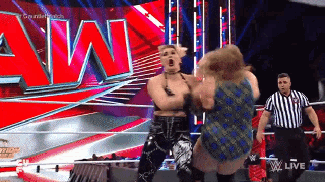 two women are fighting in a wrestling ring with a referee in front of a wwe logo