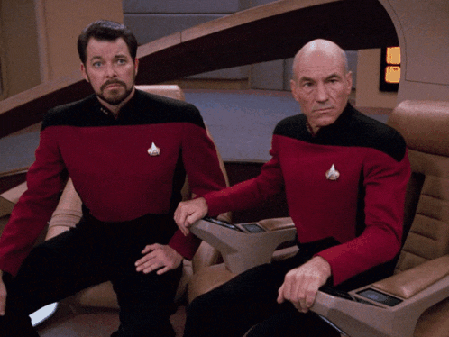 two men in red and black uniforms are sitting in chairs