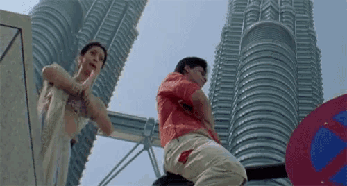 a man in a red shirt is kneeling down in front of a building
