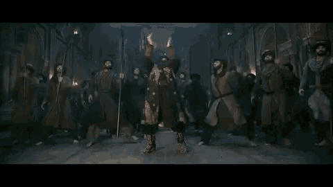 a man with a beard is dancing in front of a crowd of men .