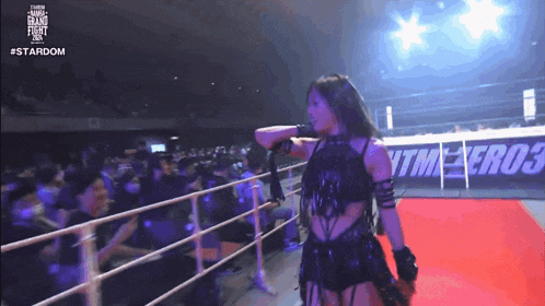 a female wrestler stands in front of a crowd and a sign that says #stardom