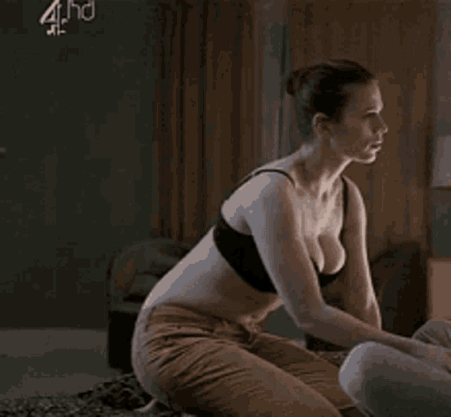 a woman in a black bra is touching her breast .