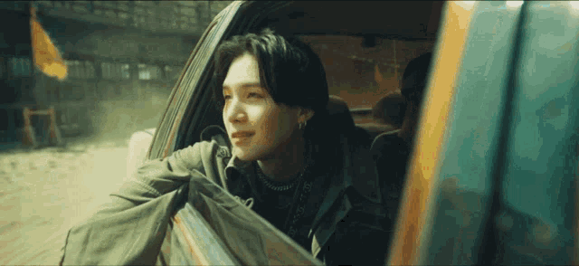 a man is sitting in a car looking out the window .