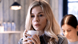 a woman is drinking a cup of coffee in a restaurant .