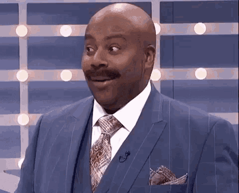 a man in a suit and tie is making a surprised face while sitting on a stage .