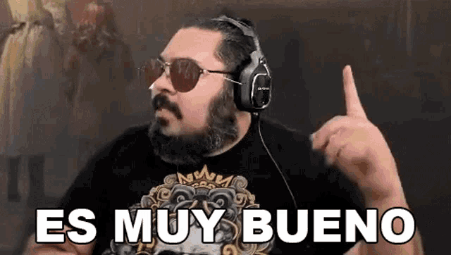 a man with a beard and sunglasses is wearing headphones and making a point .