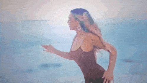 a woman in a brown swimsuit is running on the beach .