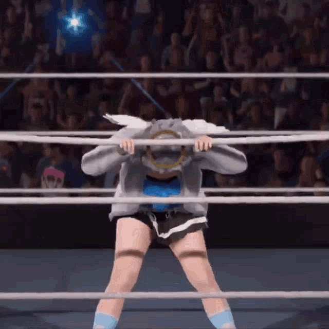 a woman is standing in a wrestling ring holding ropes