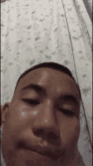 a man with a shaved head is making a funny face while sitting on a bed .