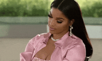 a woman wearing a pink shirt and a necklace is sitting down .