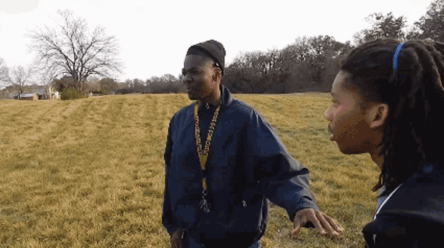 two men are standing in a field and one has a lanyard around his neck that says ' justice ' on it