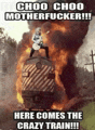 a man is standing on top of a train with a huge explosion behind him .