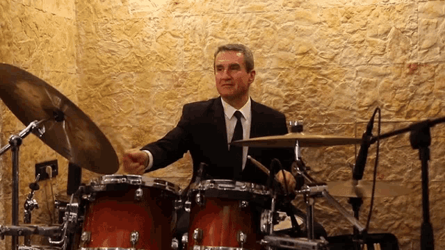 a man in a suit and tie plays the drums