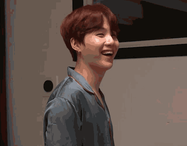 a young man with red hair is smiling and wearing a blue pajama shirt