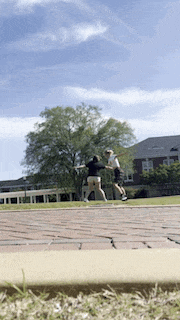 a man and a woman playing frisbee on a brick sidewalk