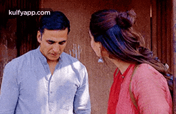 a man and a woman are standing next to each other in front of a building .