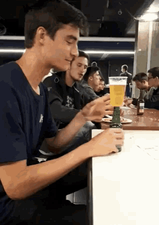 a man sitting at a table with a bottle of beer