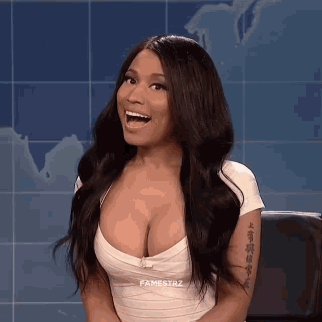 a woman with a tattoo on her arm is sitting in front of a map and smiling .