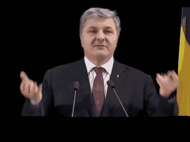a man in a suit and tie is giving a speech
