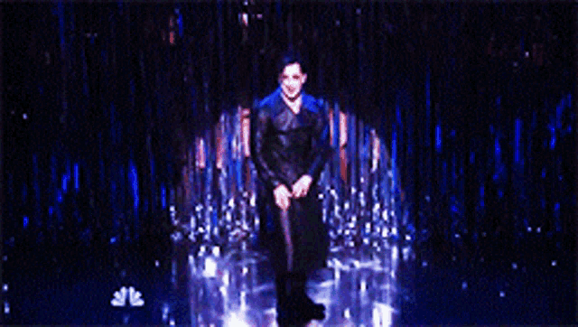 a man in a black coat is dancing in a dark room