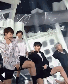a group of men are dancing on a stage and one of them is sitting on another man 's lap