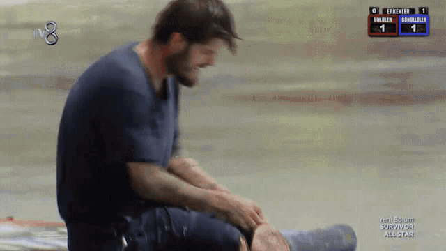 a man in a blue shirt is kneeling down in front of a screen that says survivor all star