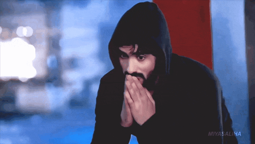 a man in a black hoodie covering his mouth with his hands and the words miyasalha on the bottom right