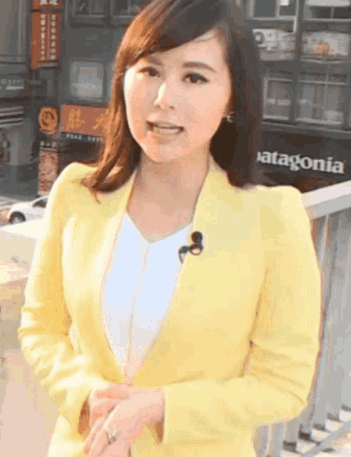 a woman wearing a yellow jacket is standing in front of a patagonia store