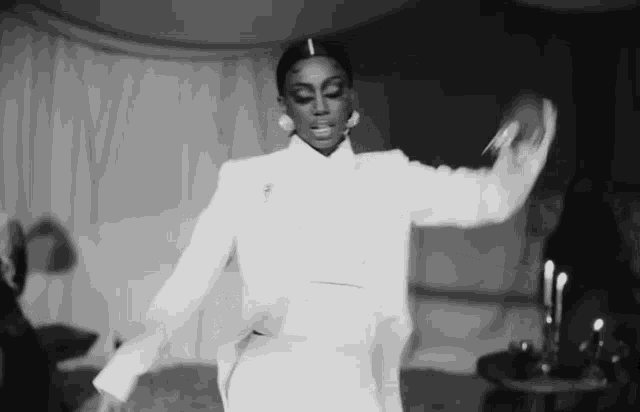 a black and white photo of a woman in a white suit and dress dancing .