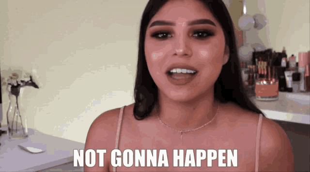 a woman says " not gonna happen " in front of a makeup table
