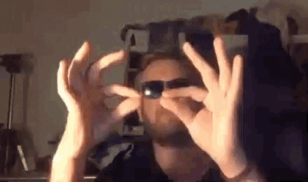 a man is holding a pair of binoculars in his hands in front of his face .