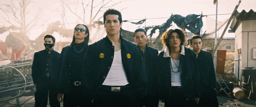 a group of young men are standing in a line and one of them has a yellow patch on his jacket that says ' i '