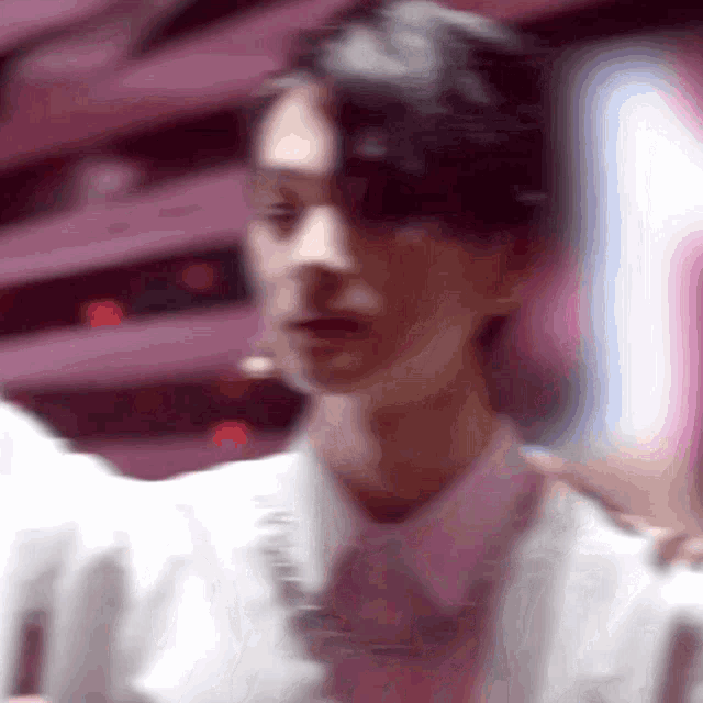 a blurry picture of a man in a white jacket and pink shirt