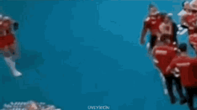 a blurred image of a group of people standing on top of a blue surface .