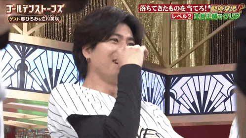 a man in a striped shirt is covering his nose with his hand