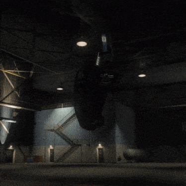 a car is hanging upside down in a dark warehouse with a fire escape