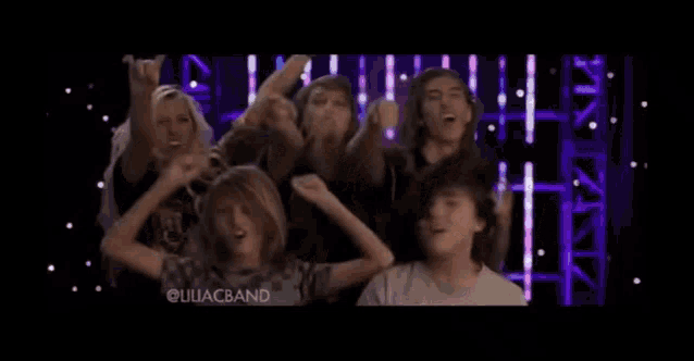 a group of people are dancing in front of a purple background