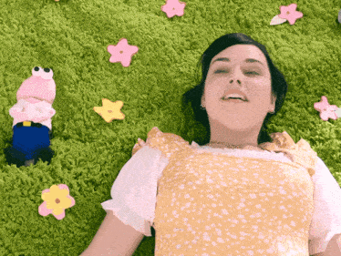 a woman laying on a green carpet with flowers