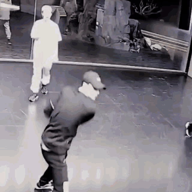 a man in a baseball cap is dancing in front of a mirror in a room .