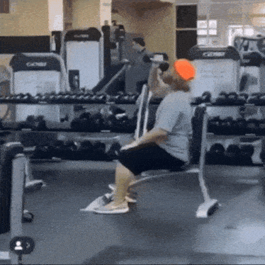 a man is sitting on a bench in a gym lifting a dumbbell ..