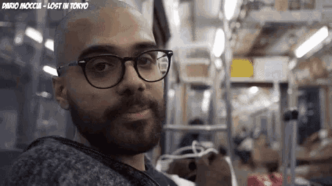a man with glasses and a beard looks at the camera with the words dario mocchi - lost in tokyo above him