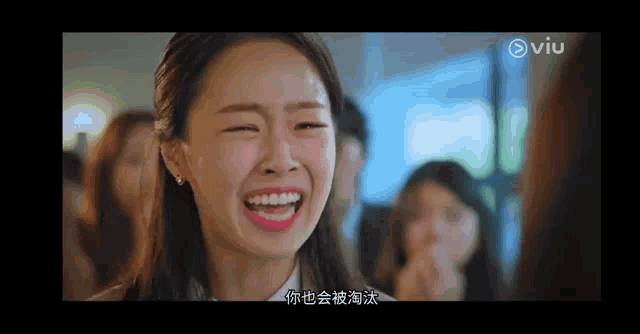 a woman is laughing with her eyes closed in front of a group of people .