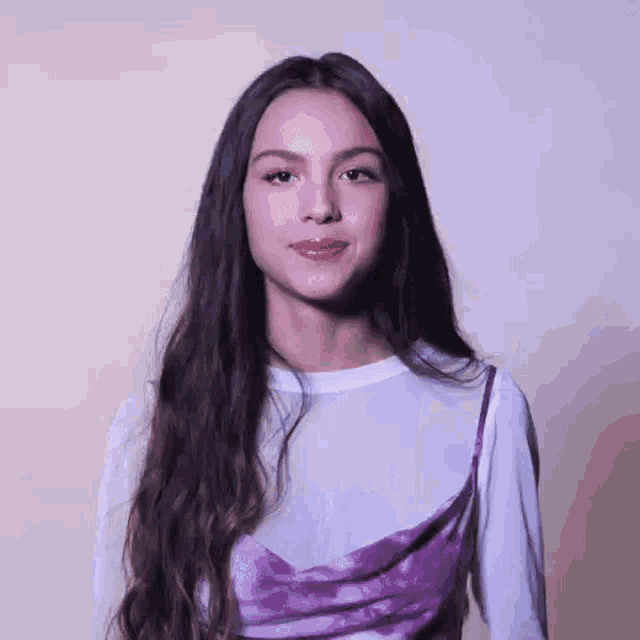 a close up of a woman with long hair wearing a purple dress and a white shirt .